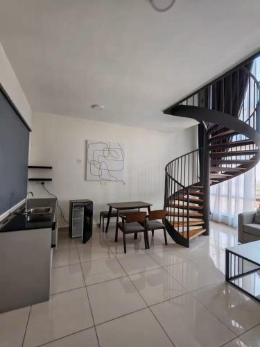 a living room with a table and a spiral staircase at The Apple Melaka in Melaka