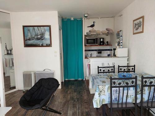 Cette chambre comprend une table, des chaises et un rideau bleu. dans l'établissement Ty Charcot, à Bénodet
