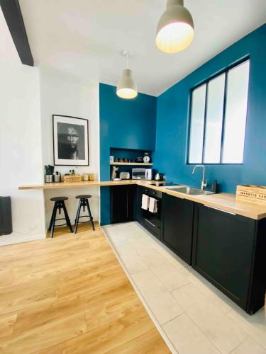 une cuisine avec des murs bleus et un comptoir. dans l'établissement Expérience loft à 2 pas du front de mer, au Havre