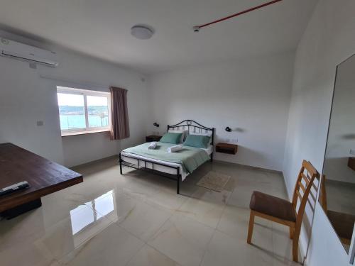a bedroom with a bed and a table and a chair at Sensi Hotel in Marsaskala
