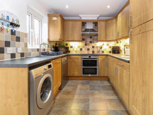 a kitchen with wooden cabinets and a washer and dryer at 19 Stablefield Way in Great Yarmouth