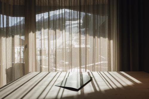 a bedroom with a large window with curtains at Haunold Homes in San Candido
