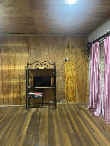 a room with a wooden floor and a shelf with a television at Family Homestay in Labasa