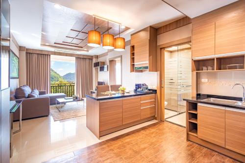a kitchen with wooden cabinets and a living room at Hillside Residence Khaoyai in Mu Si