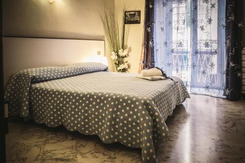 - une chambre dotée d'un lit avec des draps en points de polka et d'une fenêtre dans l'établissement Foresteria Del Pescatore, à La Spezia