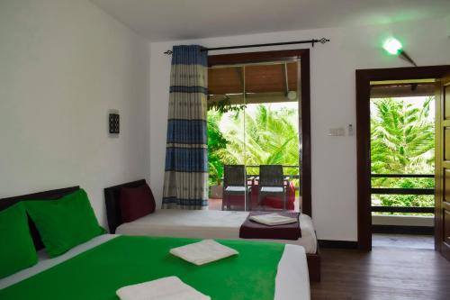 a bedroom with two beds and a sliding glass door at Hotel Green Garden in Trincomalee
