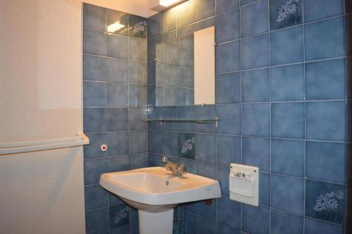 La salle de bains est pourvue de carrelage bleu, d'un lavabo et d'un miroir. dans l'établissement NP200-312 Appartement 2 pièces cabine Narbonne Plage, à Narbonne-Plage