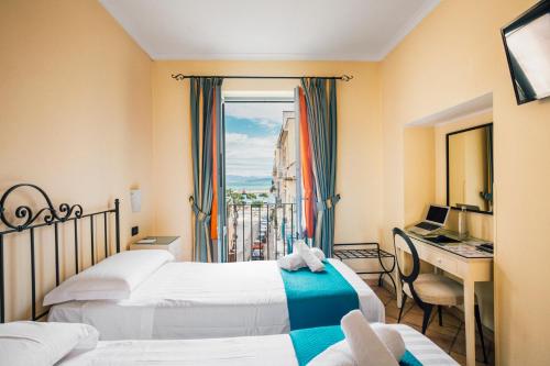 a hotel room with two beds and a desk and a window at Quartuccio - Albergo Diffuso - Gaeta in Gaeta