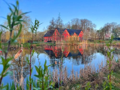 a red house is reflected in the water of a lake at Schlossgut Gross Schwansee in Groß Schwansee