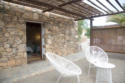 two white chairs sitting under a stone building at Rural Rugama in Puerto del Rosario
