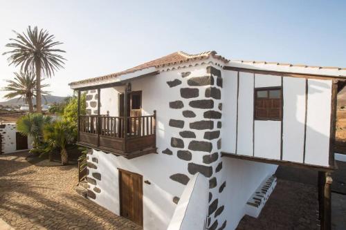 a white house with a balcony and a palm tree at Rural Rugama in Puerto del Rosario