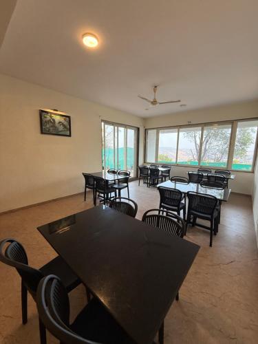 a dining room with tables and chairs and windows at Wonder Mist Resort, Mahabaleshwar in Mahabaleshwar