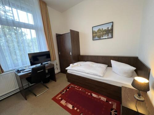 a bedroom with a bed and a desk with a computer at Hotel Seeschlösschen in Groß Köris