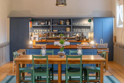 a kitchen with a wooden table and blue cabinets at Belchamp Hall Stables in Belchamp Otten