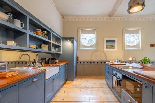 a large kitchen with blue cabinets and a wooden floor at Belchamp Hall Stables in Belchamp Otten