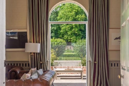 a living room with a couch and an open door at Belchamp Hall Stables in Belchamp Otten
