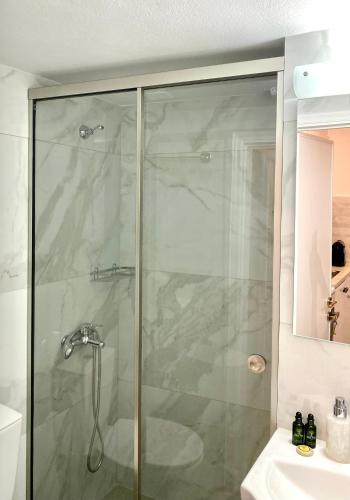 a bathroom with a glass shower with a sink at Nennella's House in Ágios Rókkos
