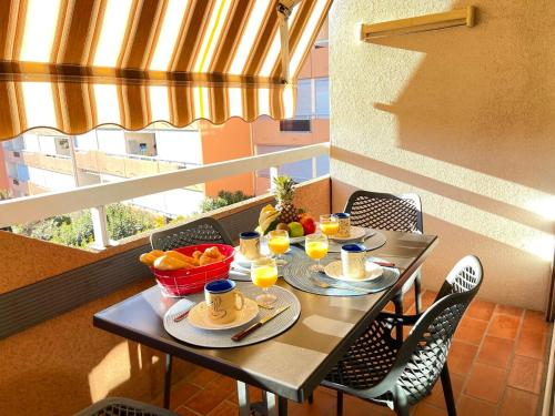 une table avec des tasses et des assiettes de nourriture sur un balcon dans l'établissement Cap Raphaël YourHostHelper, à Saint-Raphaël