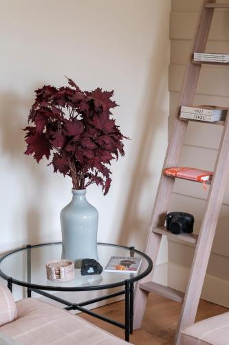 a glass table with a vase with a flower on it at The Old Livery - An Elegant Bolthole with EV Parking in Burford
