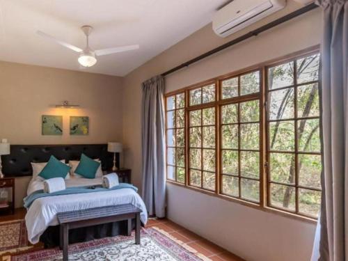 a bedroom with a bed and large windows at Ndumu Safari Resorts in Jozini