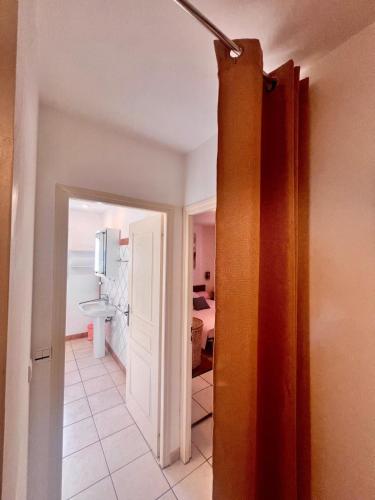 un couloir avec une porte menant à une salle de bains. dans l'établissement Maison Ondella, proche Santa Giulia, à Porto-Vecchio