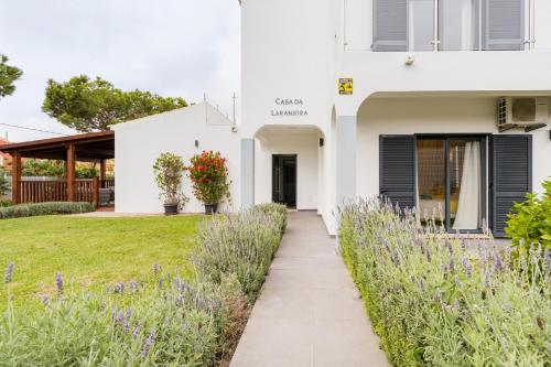 una casa bianca con fiori viola e un passaggio pedonale di Villa Oasis 4-Bedroom Retreat with Pool in Vilamoura a Quarteira