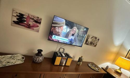 a tv hanging on a wall above a wooden cabinet at G&D Suite Apartment in Caltanissetta