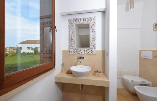 ein Badezimmer mit Waschbecken, Toilette und Spiegel in der Unterkunft Masseria Autigne in Otranto