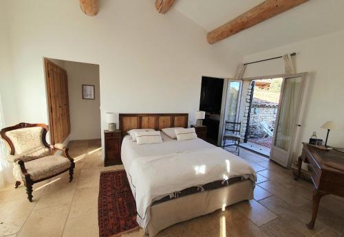 une chambre avec un grand lit et une chaise dans l'établissement Havre de paix à Gordes avec piscine chauffée, à Gordes