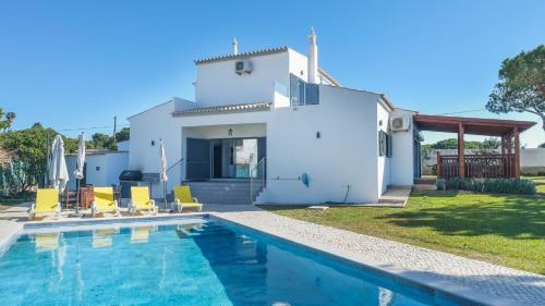 a villa with a swimming pool in front of a house at Casa Da Laranjeira- Serene 4Bedroom 4Bath Pool & Garden Villa, 10 mins to Vilamoura Marina in Quarteira