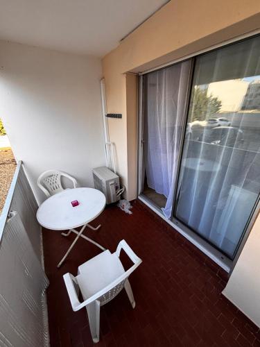 d'un balcon avec une table et des chaises blanches ainsi qu'une fenêtre. dans l'établissement Studio Ocean Crest avec clim et wifi, à La Grande Motte