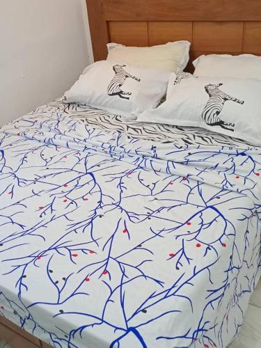 a bed with a blue and white comforter on it at Studio moderne où tout est Neuf, Cuisine, Couvert,ClimatiséWifi haut débit , Smart TV à bertoua in Bertoua
