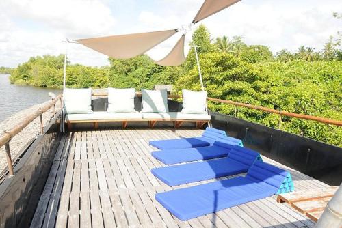 a boat with blue lounge chairs and an umbrella at Yathra Houseboat in Bentota