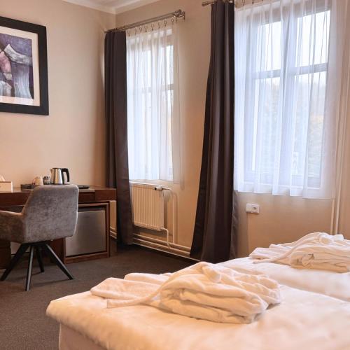 a bedroom with a bed and a desk and windows at Hotel Zelený dům in Dolní Poustevna
