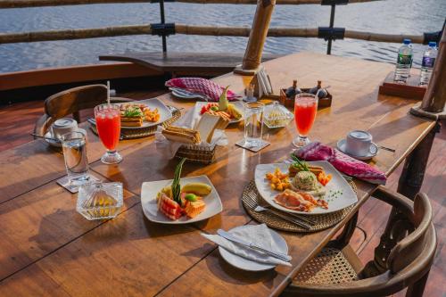 a wooden table with plates of food and drinks at Yathra Houseboat in Bentota