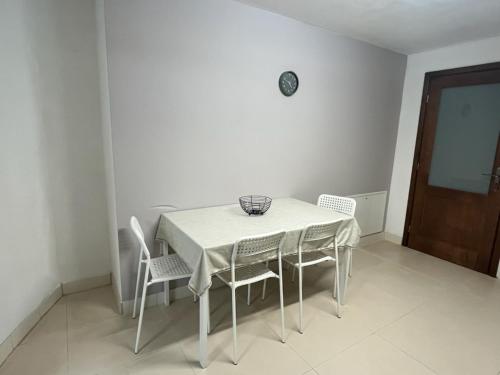 a white dining room table with chairs and a clock on the wall at Górska Kryjówka in Nowy Targ