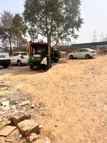 a small vehicle parked in a dirt lot with cars at Apna Homes Stay & Hotel I Gurugram I Sector-71 in Gurgaon
