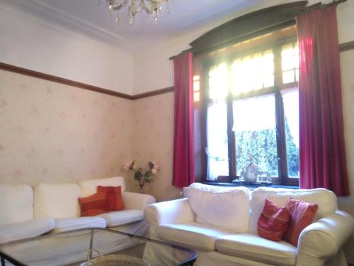 a living room with two white couches and a window at Villa Belle Epoque in Hamoir