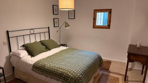 a bedroom with a bed with green pillows and a desk at Veratha House in Candeleda