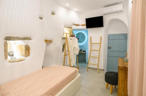 a bedroom with a bed and a desk and a tv at Idothea guest house in Amorgos
