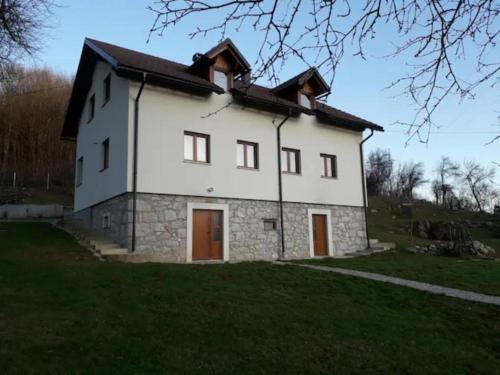 a large white house on top of a green field at Holiday House Marija in Otočac