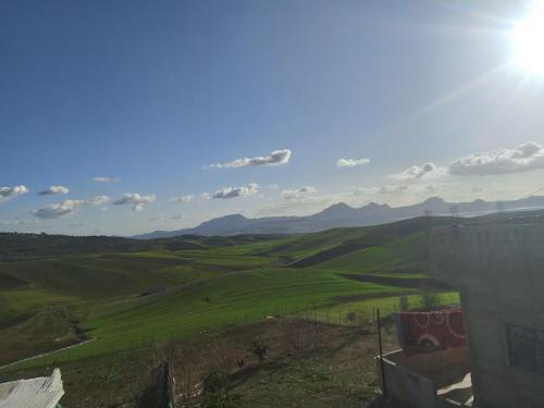 a view of a green field with mountains in the background at L'ile de caroubier in Taounate