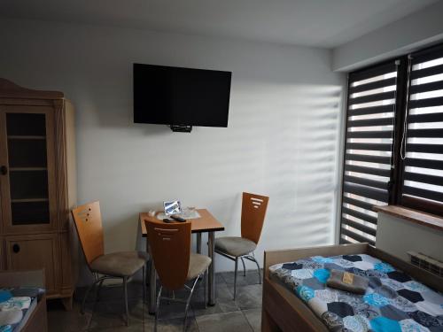 a room with a table and a television on the wall at Dom Lawendowy in Lubasz