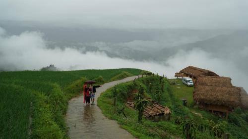 two people walking down a dirt road with an umbrella at Hoàng Su Phì - Móng Ngựa Homestay in Ha Giang