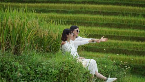 a man and a woman sitting in the grass at Hoàng Su Phì - Móng Ngựa Homestay in Ha Giang