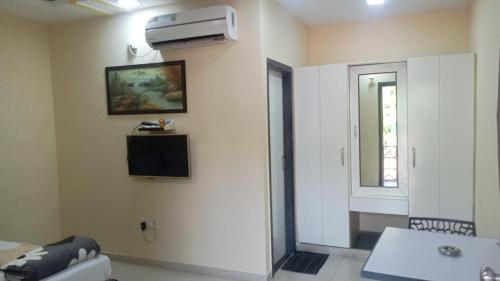 a living room with a television on the wall at Giriraj Garden Resort in Vāgholi