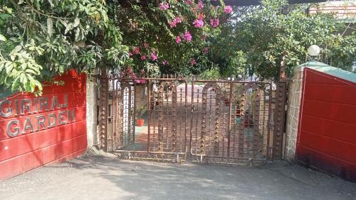 a red gate with a red fence with pink flowers at Giriraj Garden Resort in Vāgholi