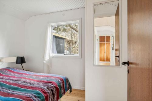 a bedroom with a bed and a window and a mirror at Charming Cottage In Raageleje in Vejby