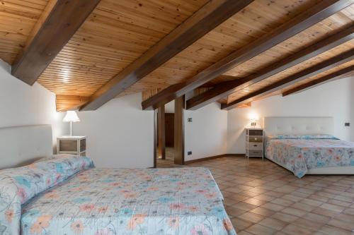 a bedroom with two beds and a wooden ceiling at Casetta dei Daini in Orio al Serio