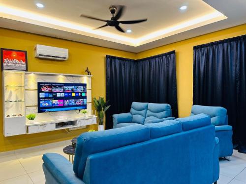 a living room with blue couches and a flat screen tv at MutiaraMaxx Homestay in Kampong Jelatang